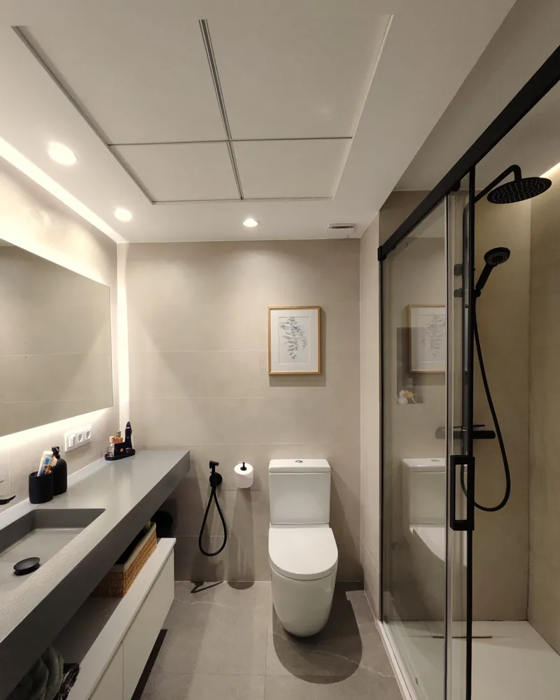 Baño en suite con mampara de vidrio y lavabo de microcemento