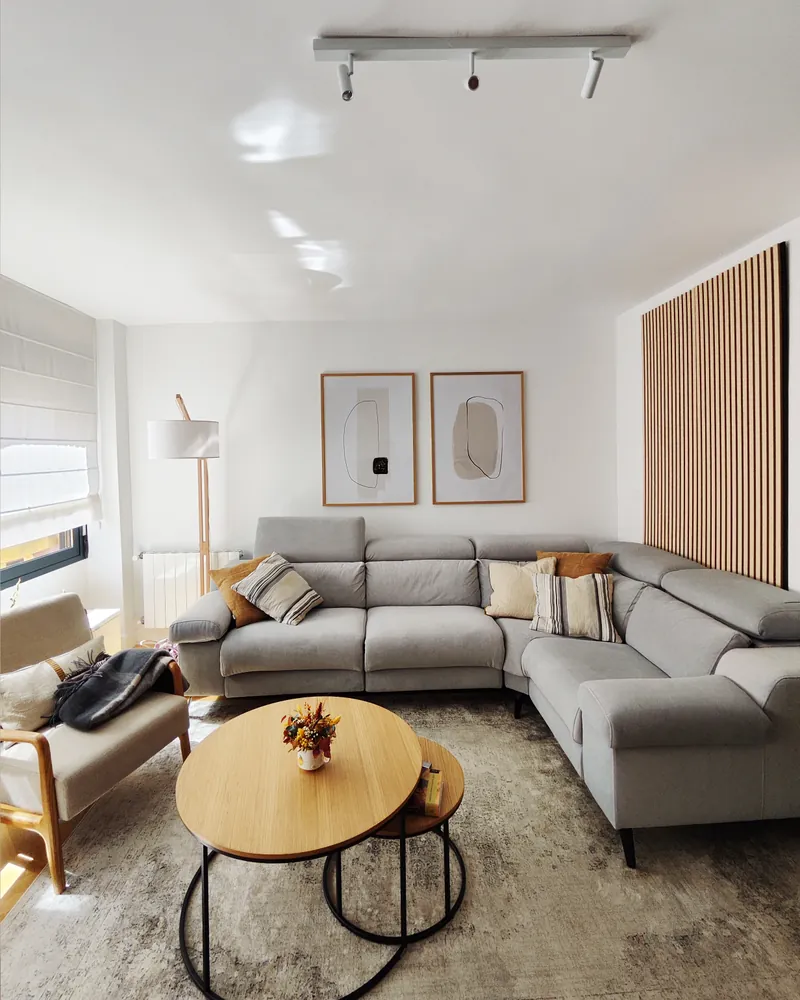 Salón de Casa Loaces con el sofá gris y el panel de lamas de madera