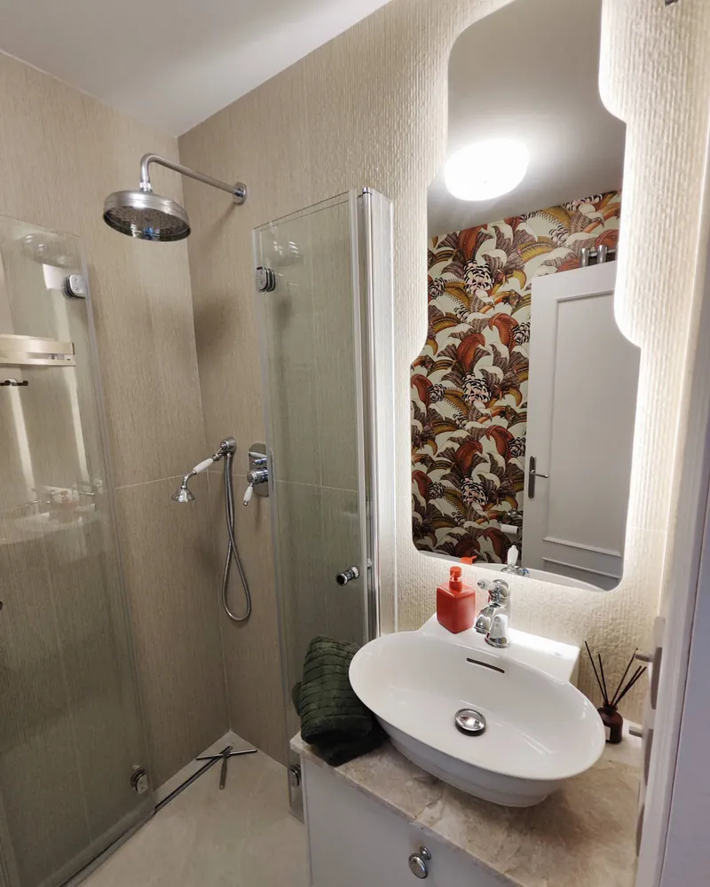 Baño con ducha y papel pintado de motivos vegetales
